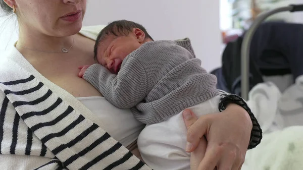 Anne, yeni doğmuş bebeğini göğsüne yakın bir yere yatırıyor, sıcaklık ve bakım yayıyor. Huzurlu bir ev ortamında anne ve çocuk arasındaki şefkat ve derin bağ