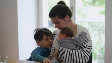 Anne hem yeni doğan hem de büyük çocuğunu yanında tutarak aile içinde paylaşılan sıcaklığı, sevgiyi ve bağlantıyı vurgulayan samimi ve huzurlu bir aile anı yaratıyor..