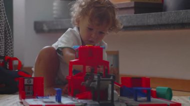 Oyuncak garajda ve arabalarla oynayan küçük çocuk, odaklanmış ifade, yaratıcı oyun sırasında şekilleri ve hareketleri keşfetmek ve evde erken çocukluk öğrenimi