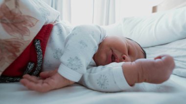 Yeni doğmuş bir bebeğin kollarını ve ellerini uzatarak uyuduğu ilk çocukluk sükunetini yakaladığı yakın plan..