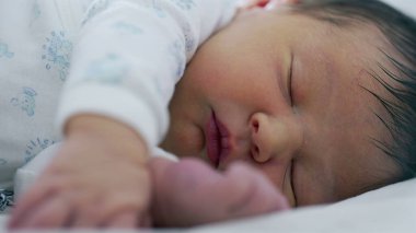 Yeni doğan bebek el ve ayakla uyuyor. Bebeklik döneminin hassas ve nazik doğasını vurguluyor..