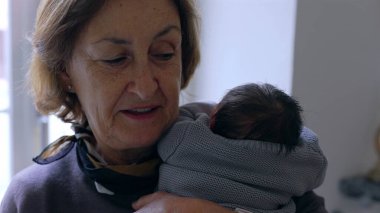 Anneanne yeni doğmuş bir bebeği omzuna yakın tutuyor, huzurlu bir ifadeyle, sevgi ve bağın hassas bir anını yakalıyor..
