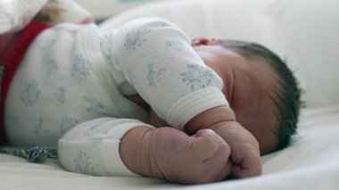 Yeni doğan bebek kıvrılıp uyuyor. Rahat ve güvenli bir ortamda çocukluğunun huzurunu ve huzurunu vurguluyor..