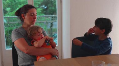 Anne, Bebek Yeme Aperatifi 'yle otururken, Kardeş, Konforlu Aile Evi' nde Yemek Masası 'nda oynuyor..