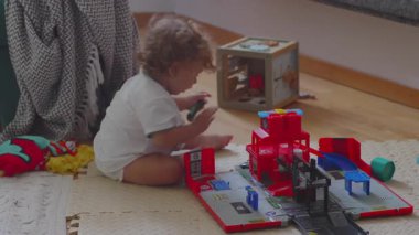 Oyuncak garajı ve arabalarla oynayan, hayal gücüne odaklanmış, evde sakin bir çocukluk anında şekilleri ve hareketleri keşfeden bir çocuk.