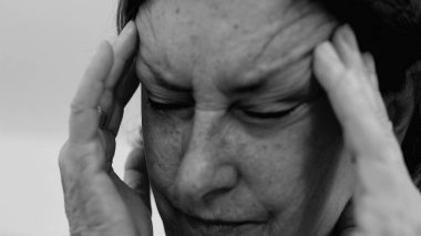 Yaşlı kadın yakın plan, gözleri kapalı, iki eli şakaklarına baskı yapıyor, derin kırışıklıklar ve acı dolu ifade, şiddetli stres veya baş ağrısı SD 480p