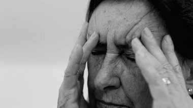 Yaşlı kadın yakın plan, gözleri kapalı, iki eli şakaklarına baskı yapıyor, derin kırışıklıklar ve acı dolu ifade, şiddetli stres veya baş ağrısı SD 480p
