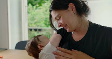 Anne ve bebek sevgi dolu bir anın tadını çıkarıyorlar, bebek rahatça kollarına yerleşmiş, sıcak, sıcak bir ev ortamında aralarındaki sevgi ve bağın altını çiziyor - SD 480p