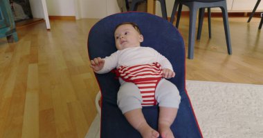 Bebek bir fedaide uzanıyor, mutlu ve rahat görünüyor, rahat bir ev ortamında bir anlık rahatlığın tadını çıkarıyor, erken çocukluk SD 480p 'sinin masumiyetini ve huzurunu vurguluyor.