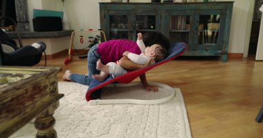 Büyük kardeş, bir fedainin üzerindeki küçük kardeşle şefkatle iletişim kuruyor. Bir yuva ortamında aralarındaki güçlü bağı ve sevgiyi vurgulayan dokunaklı ve sevgi dolu bir an yaratıyor.