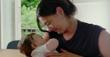 Anne ve bebek sevgi dolu bir anın tadını çıkarıyorlar, bebek rahatça kollarına yerleşmiş, sıcak, sıcak bir ev ortamında aralarındaki sevgi ve bağın altını çiziyor - SD 480p