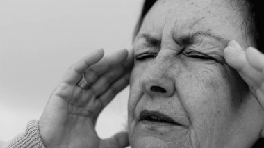 Yaşlı kadın yakın plan, gözleri kapalı, iki eli şakaklarına baskı yapıyor, derin kırışıklıklar ve acı dolu ifade, şiddetli stres veya baş ağrısı SD 480p