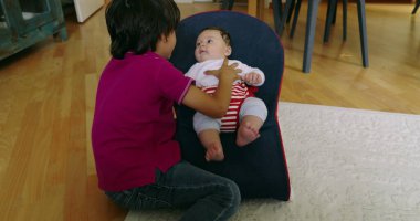 Büyük kardeş, bir fedainin içinde küçük kardeşiyle etkileşime giriyor, aralarında hassas ve sevgi dolu bir anı vurguluyor, SD 480p 'lik bir evde çocukluğun masumiyetini ve neşesini yakalıyor.