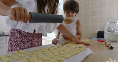 Kız ve erkek mutfaktan para kazanıyor, kız oklava kullanıyor, oğlan asistanı, aile yemekleri, takım çalışması, parlak ev dekorasyonu, öğrenme ve bağ kurma ile uğraşan çocuklar