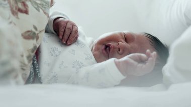 Yeni doğmuş bebek yatakta ağlıyor, rahatsız edici bir şekilde elini kaldırıyor. Bebeğin yüzünde sıkıntı var ve jestler ajitasyon-SD 480p gösteriyor.