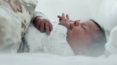 Yeni doğmuş bebek yatakta ağlıyor, rahatsız edici bir şekilde elini kaldırıyor. Bebeğin yüzünde sıkıntı var ve jestler ajitasyon-SD 480p gösteriyor.