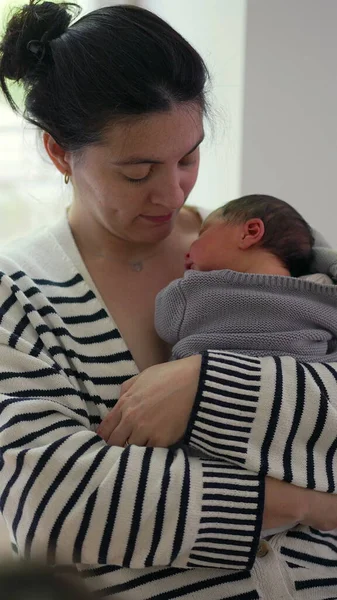 Anne yeni doğmuş bebeğini göğsüne yakın tutuyor, şefkatli bir ifadeyle aşağıya bakıyor. Anne ve çocuk arasındaki güçlü bağ sakin, kapalı alan ayarlı SD 480p