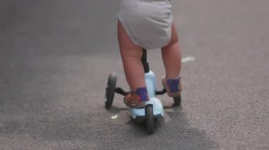 Park yolunda scooterla gezen küçük çocukların yakın plan fotoğrafları azimli bir şekilde ileriye doğru iten küçük çocuklar, açık havada eğlenceli yaz aktiviteleri ve erken gelişim anı.