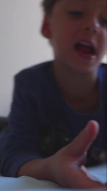 Yatakta uzanmış akıllı telefona bakan çocuğun yakın çekimi yumuşak bir gülümsemeyle, samimi bir çocukluk anısı odaklanmayı, merakı ve sessiz bir nişanı gösteriyor.