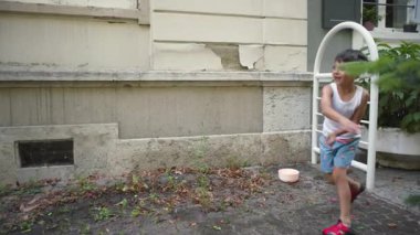 Genç bir çocuk yaz etkinliği sırasında kamerasız birine su balonu fırlatıyor.