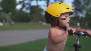 Bisikletli bir çocuk giyer sarı bir miğfer takar, giyer ve merakla geleceğe bakar, yaz etkinlikleri sırasında parkın çevresini keşfederdi.