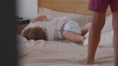 Yeni yürümeye başlayan çocuk, yanında duran büyük kardeşe bakıyor. Merakla, bağlantıyla ve kaygısız çocukluk döneminde kaynaşma ile dolu eğlenceli bir an.