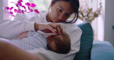 Anne, anne ve çocuk arasında şefkatli ve sevgi dolu bir ortamda bebeğini emzirirken nazikçe başını okşuyor..