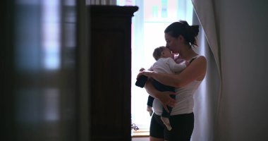 Anne bebeğini hafifçe aydınlatılmış bir odada kucağında tutuyor, bebeğini huzurlu, şefkatli ve şefkatli bir anda kucaklıyor, sevgi ve sakinlik gösteriyor. SD 480p