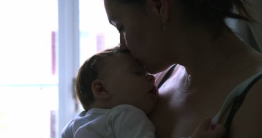 Anne, uyuyan bebeğini kafasından öper, pencerenin yanında durup sevgi ve şefkat göstererek, gün ışığıyla sahneyi aydınlatır.