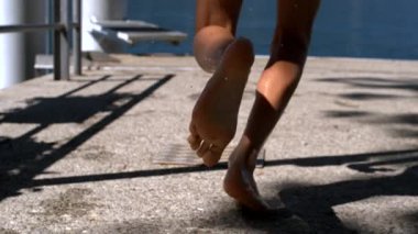 Yakından göl kenarına doğru koşan bacaklar, havada su damlacıkları, açık havada yaz macerası, deniz kenarında eğlenceli çocukluk aktiviteleri.