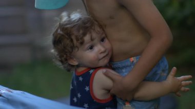 Bebek kucaklaması ağabey yavaş çekim, açık havada şefkatle kucaklaşma, yakın sevgi dolu an kardeş sevgisi, rahatlığı ve duygusal bağ.