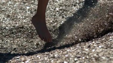 Çıplak ayaklı çocuk oyun parkındaki tahta parçalarında oynuyor, yavaş çekim yakın çekim doğal hareketi, kaygısız yaz enerjisini ve açık hava çocukluk özgürlüğünü gösteriyor.