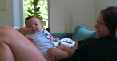 Anne bebekle kanepede uzanıyor, huzurlu bir evde dinleniyor, sıcak ve rahat bir oturma odasında sessiz bir bağ kurma zamanını paylaşıyor..