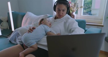 Anne, bebeğin göğsünde uyuması, kulaklık takması, dizüstü bilgisayarda çalışması, rahat ev ortamında çalışması, işi dengelemesi ve ebeveynliği