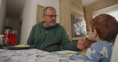 Babam gülümseyerek ve karnını doyurarak sandalyeye oturmuş, sıcak bir ev mutfağında yemek masasında eğlenceli bir ilişkiye giriyordu.