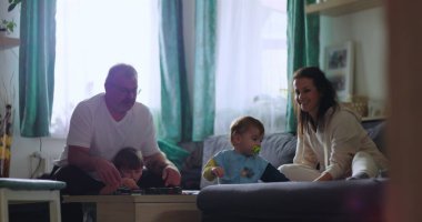 Baba ve çocuklar masanın etrafında toplandı. Genç çocuk öne doğru eğilirken, anne sıcak ve çekici aile anlarında gülümsüyordu.