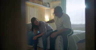 Kocası üzgün karısına destek oluyor, yatağın kenarında oturuyor, duygusal mücadeleye odaklanıyor, zihinsel sağlık farkındalığı, umutsuzluk, üzüntü ve kişisel kriz temaları