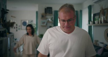 Erkek, tartışma sırasında yoğun bir ifadeyle kameraya bakıyor, kadın oturma odasında, gergin ve duygusal bir ilişki çatışması ve hüsran anı yaşıyor.