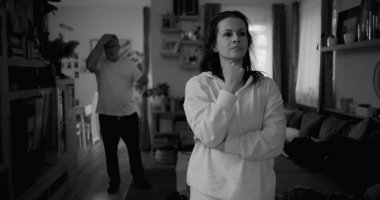 Kadın hararetli tartışmalar sırasında derin düşüncelere dalarken, arka plandaki erkek hayal kırıklığı, gerginlik ve bir çiftin ilişkilerindeki çözülmemiş sorunları işaret ediyor.