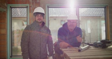 İnşaat alanındaki inşaat, takım çalışması ve güvenlik, işçilik ve adanmışlık alanlarındaki alet ve atölyenin yanında güven içinde poz veren inşaat işçileri