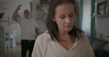 Tartışma sırasında ön planda aşağılanmış ifadeyle duran kadın, arka planda hayal kırıklığı, duygusal ve gergin ilişki çatışması içinde hareket eden erkek.