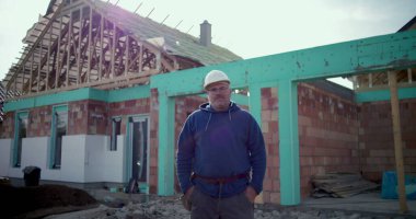 İnşaat işçisi inşaat alanında çalışıyor, devam eden projenin önünde profesyonel poz veriyor, şanlı inşaat işçisi iş yerinde çalışıyor, kararlılık ve gurur.