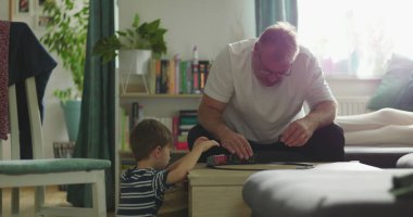 Baba, kahve masasında oyuncak tren oyunu oynayan çocukla karşılaşır. Baba ve oğul arasında samimi bir bağ kurar. Sakin ve sıcak bir oturma odası kurar.