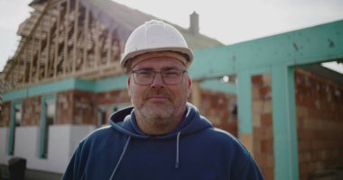 İnşaat alanındaki inşaat işçisinin yakın plan portresi, sabit şapka konusunda deneyimli, inşaat endüstrisindeki yüz, güven ve adanmışlığa odaklı.