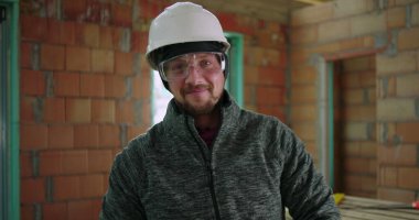 İnşaat işçisi, bina içi, güvenlik teçhizatı, miğfer ve gözlük, inşaat aletleri, sanayi bölgesi gibi görevlere odaklanmış, tamamlanmamış iç mimariye güvenle el değirmeni tutuyor.