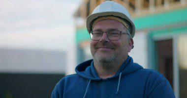 İnşaat işçisi inşaat sahasında gülümsüyor, gelişigüzel ifade ediyor inşaat projesi devam ediyor, açık hava çalışma ortamı, gündüz vakti...