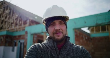 İnşaat alanında çalışan erkek inşaat işçisinin yakın plan portresi, kameraya bakan kendine güvenen profesyonel, endüstri uzmanlığı ve adanmışlığına odaklan