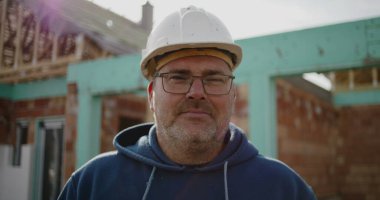 İnşaat alanındaki inşaat işçisinin yakın plan portresi, sabit şapka konusunda deneyimli, inşaat endüstrisindeki yüz, güven ve adanmışlığa odaklı.