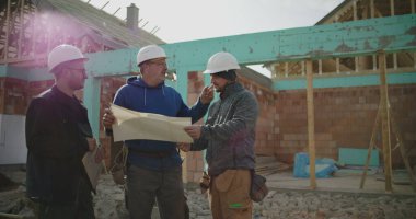 Bina planlarını inceleyen inşaat ekibi, inşaat planlarına odaklanmış tartışma, proje yönetiminde işbirliği, iş başında inşaat sektörü profesyonelleri