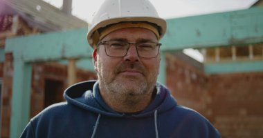 İnşaat alanındaki inşaat işçisinin yakın plan portresi, sabit şapka konusunda deneyimli, inşaat endüstrisindeki yüz, güven ve adanmışlığa odaklı.